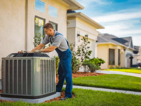 A professional HVAC technician working on a central air conditioning unit outside a modern suburban home in a Texas neighborhood under clear blue skies.