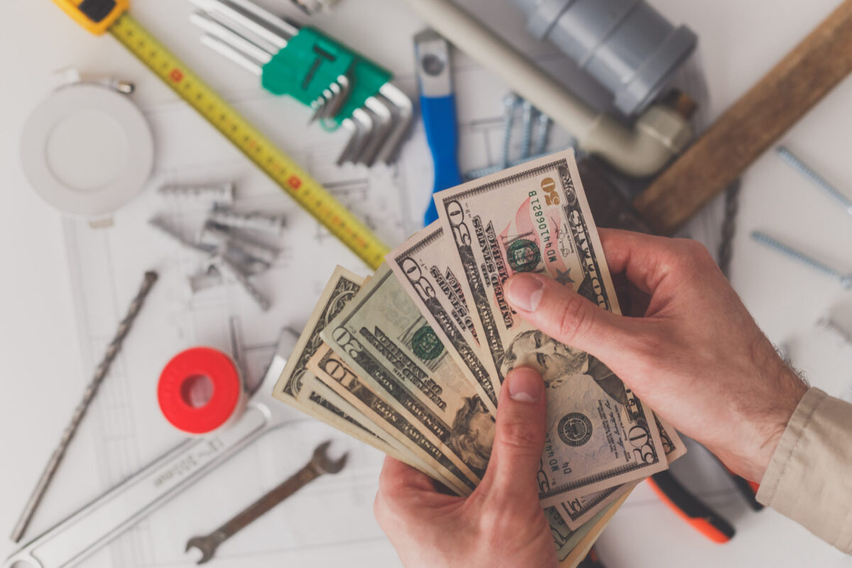 Homeowners hands counting the costs of Sewer Line Repairs.