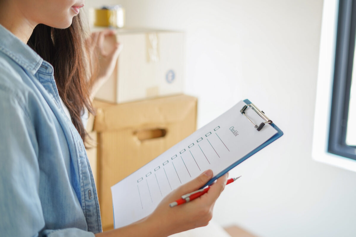 A woman with her Comprehensive AC Maintenance Checklist and a pen, set against a suburban Texas home.