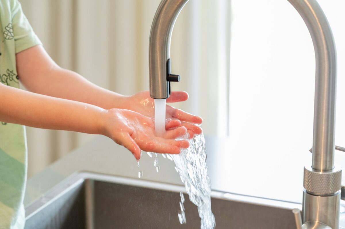 A suburban home in Texas with running warm water and a set of hands in the sink.