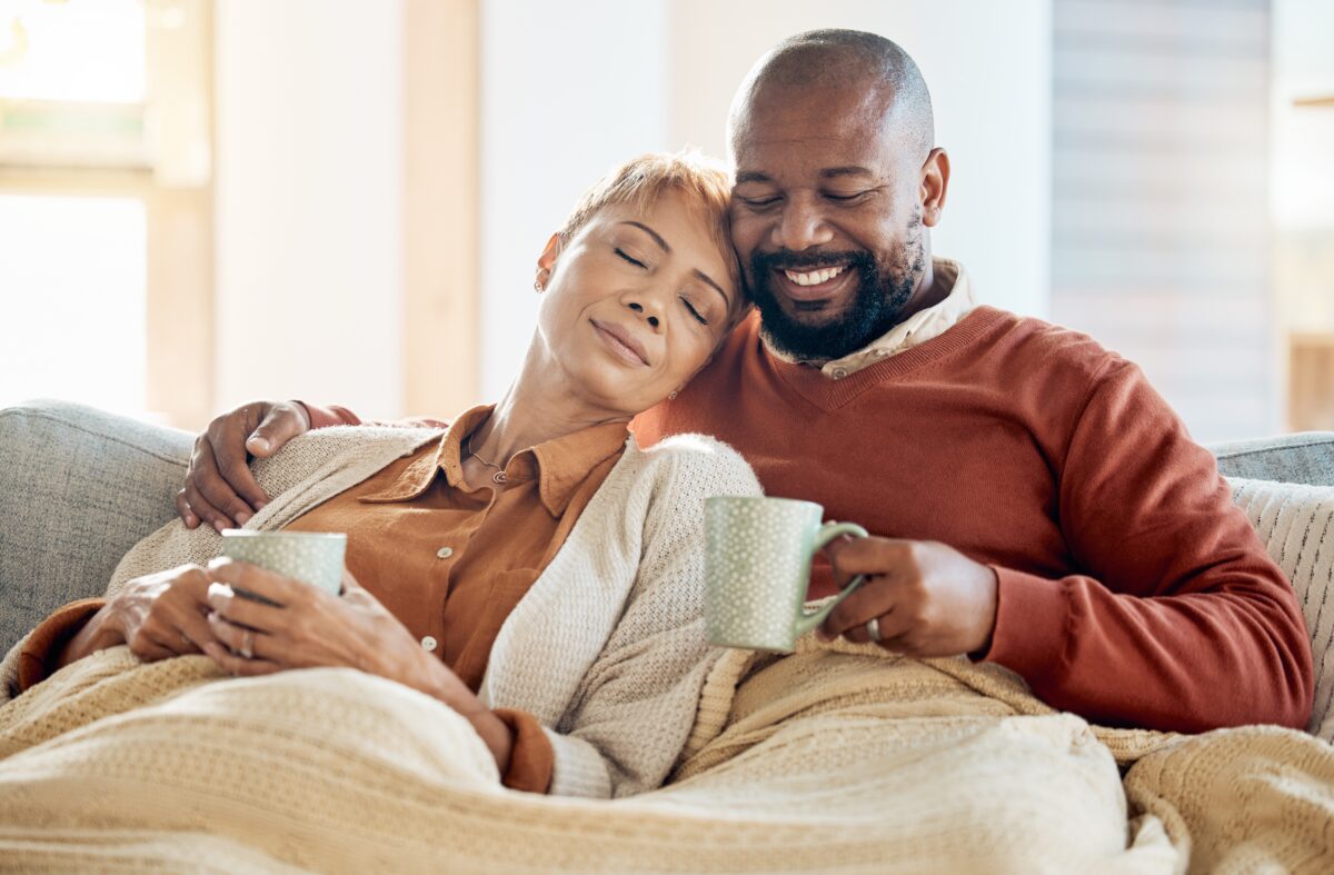 A happy family sitting on their couch with a blanket on in their warm home.